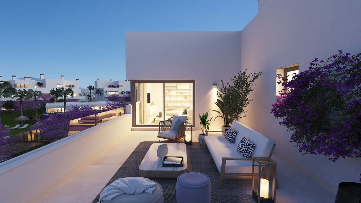 Acqua Gardens – Estepona - rooftop terrace with white outdoor sofa, bougainvillea, and illuminated interior at dusk