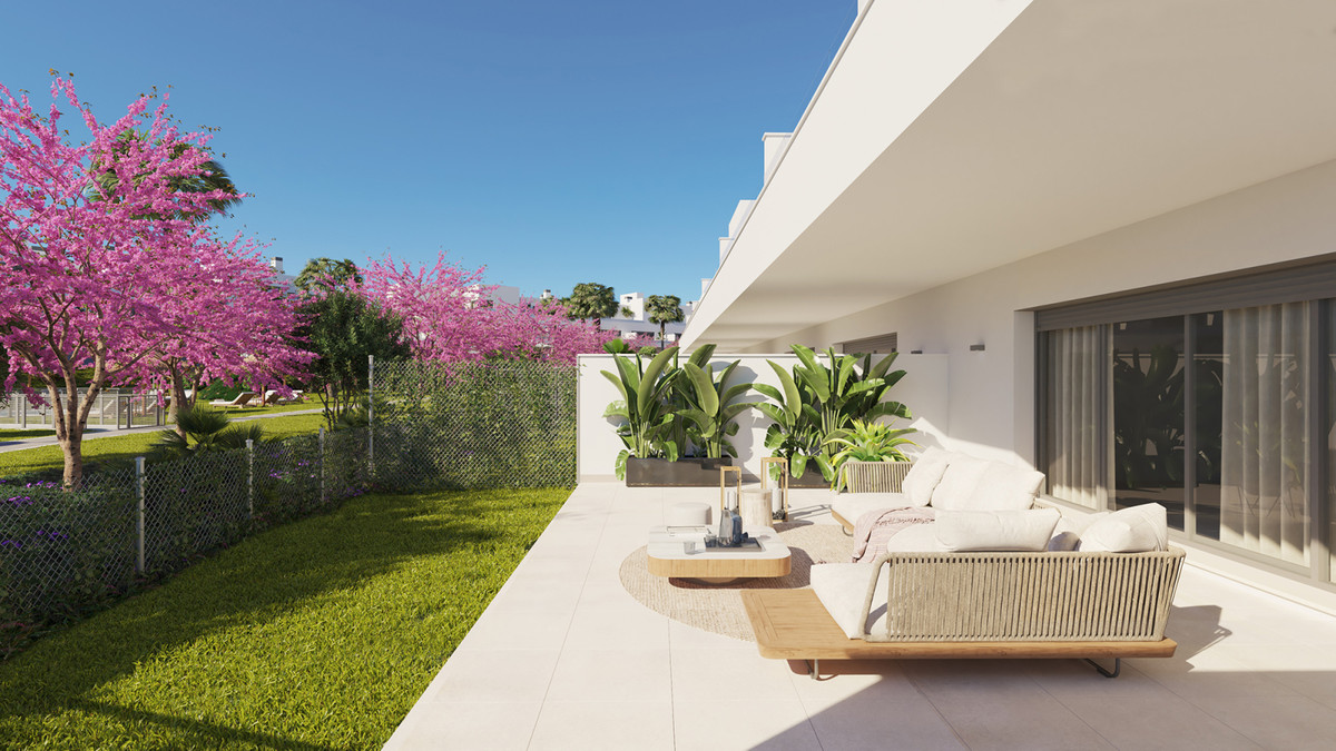 Acqua Gardens – Estepona - private terrace with outdoor lounge seating, lush garden, and flowering pink trees under a clear blue sky