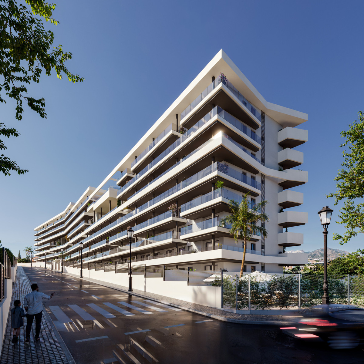 Astra Homes – Fuengirola - modern white apartment building exterior with tiered balconies and glass railings on sunny street