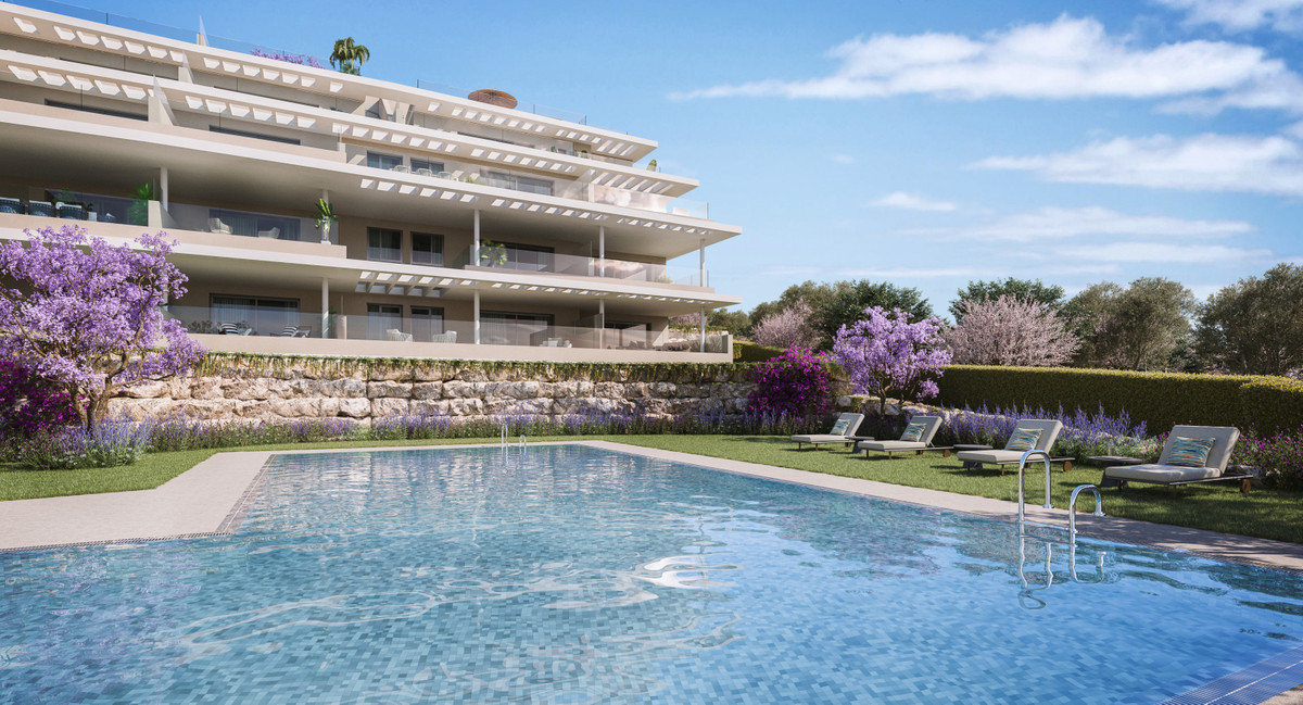 Capri – Fase 3 – Estepona - luxury residential complex with communal pool, sun loungers, and blooming purple gardens