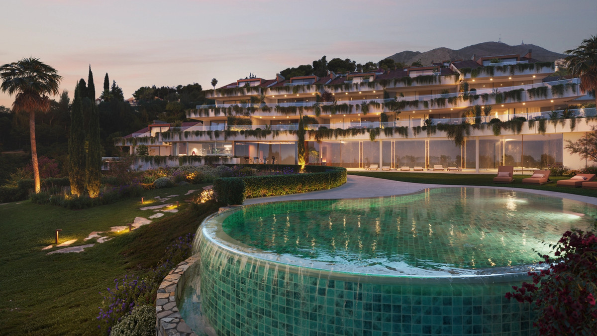 Casatalaya Residences – Benalmadena – oplyst terrasseret facade med grønflisebeklædt rund pool og landskabshaver i skumringen