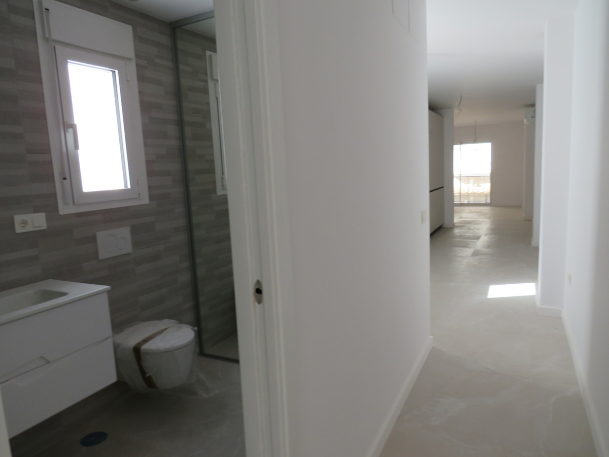 Edificio Venecia – Fuengirola - modern bathroom with wall-hung toilet and vanity unit opening onto a bright hallway corridor