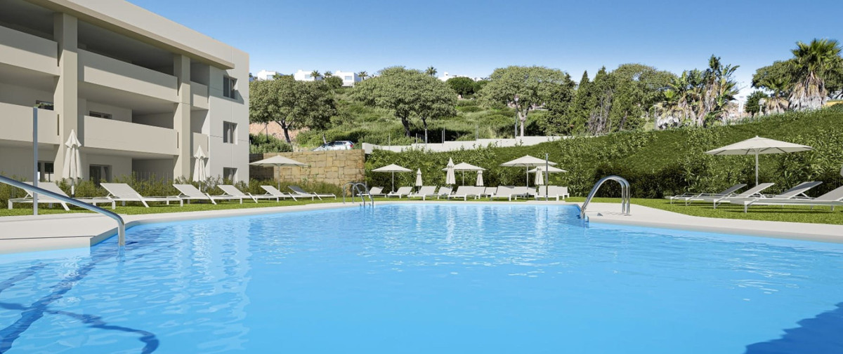 Grand Bay Apartments – Manilva - stor fælles pool med liggestole, parasоller og frodigt grønt landskab