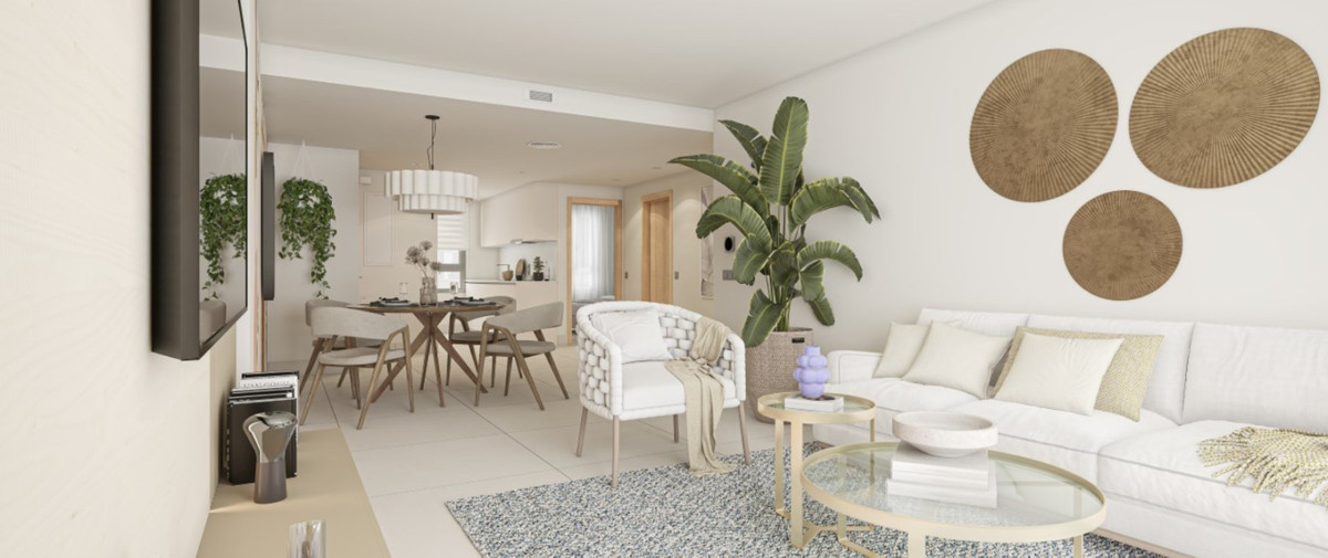 Grand Bay Apartments – Manilva - lyst åbent stue- og spiseområde med hvid sofa, rottingstol, glassofabord og tropiske planter