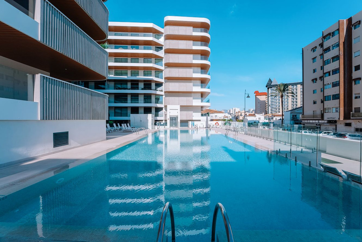 Jade Tower with Furniture – Fuengirola - outdoor swimming pool with modern curved white residential towers and clear blue sky