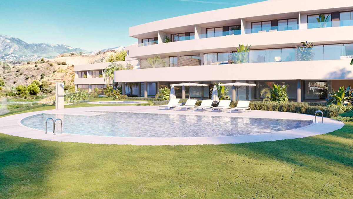 Korall – Fuengirola - ovaal gemeenschappelijk zwembad en aangelegde tuin met modern luxe appartementengebouw en bergpanorama