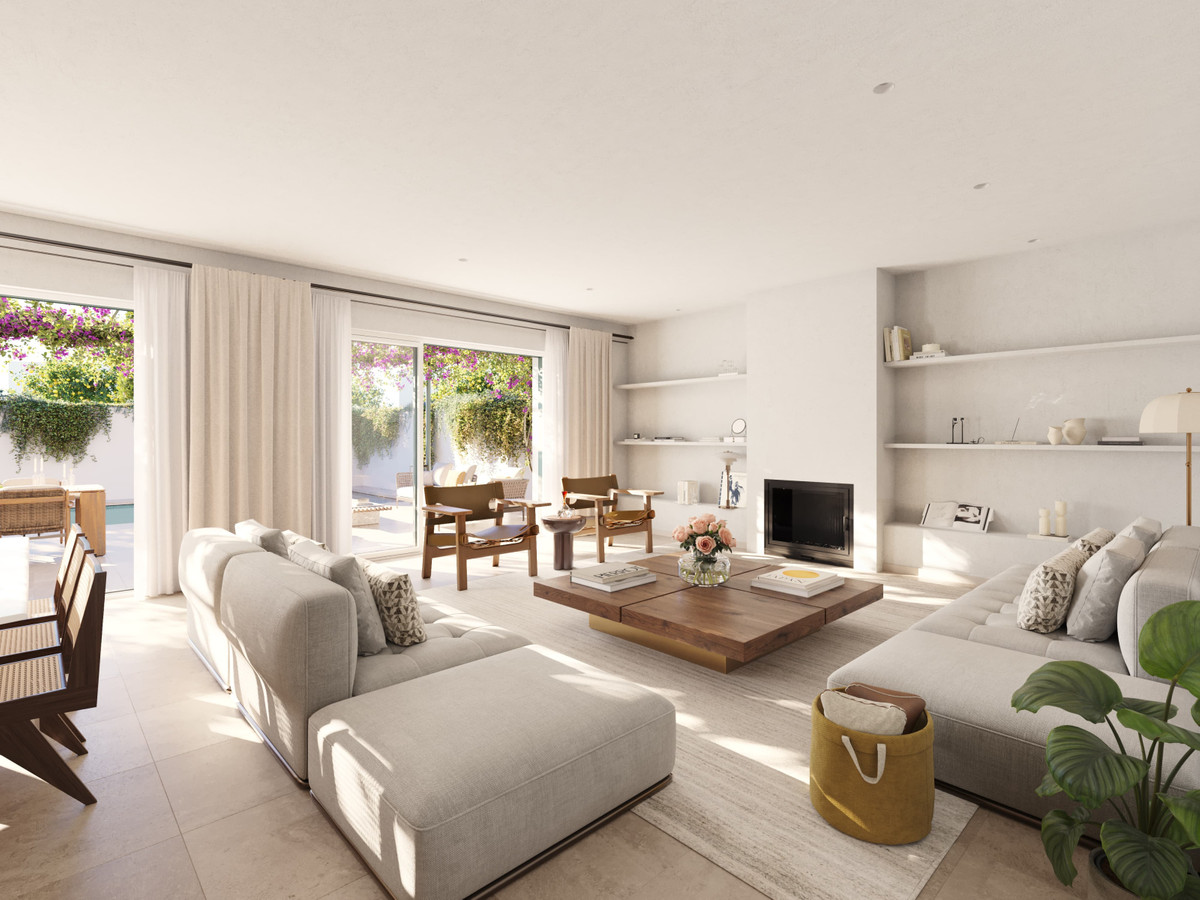 Las Villas–Sotogrande – Sotogrande - lichte open woonkamer met neutrale banken, houten salontafel, open haard en tuinterras