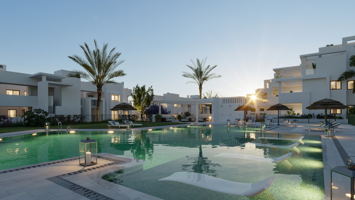 Mala Kai – Estepona – beleuchteter Gemeinschaftspool in der Abenddämmerung mit Palmen und modernen weißen Apartmentgebäuden