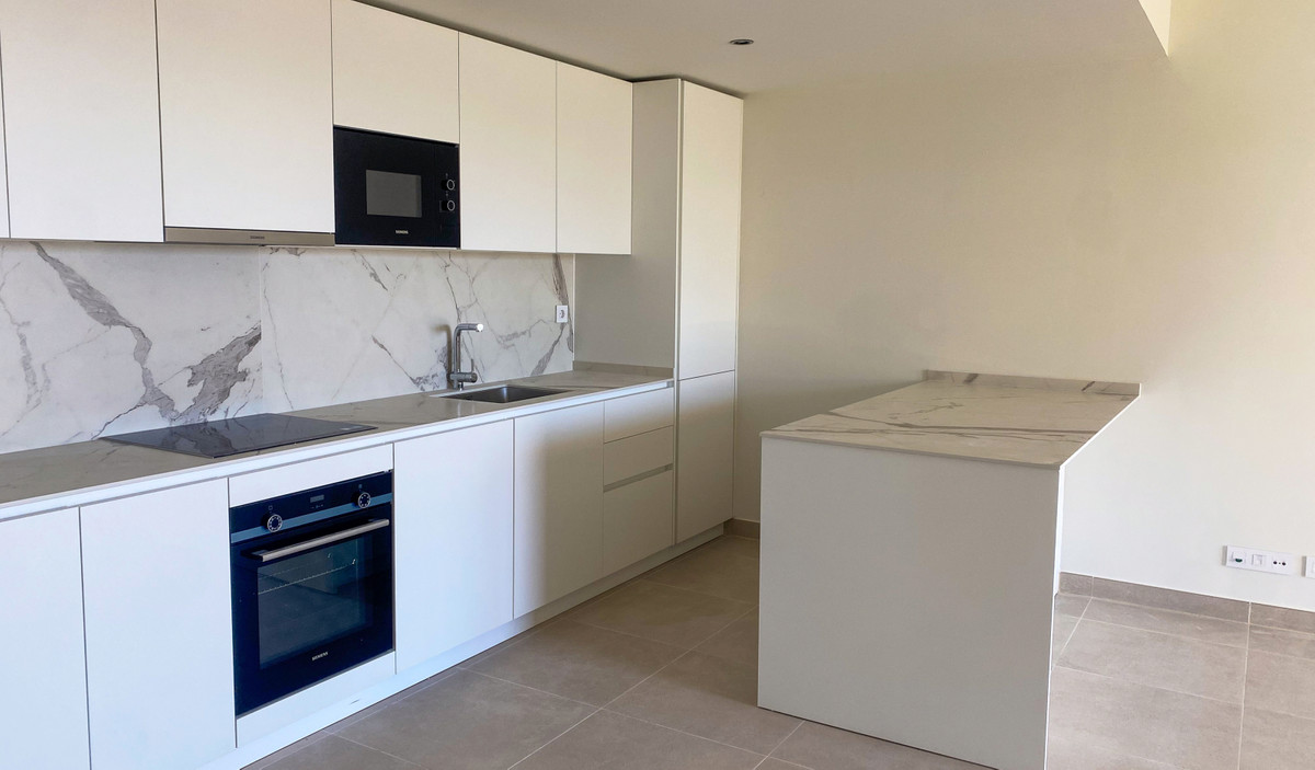 Mane Residences – Benalmadena - modern white kitchen with marble backsplash, island, and integrated Siemens appliances