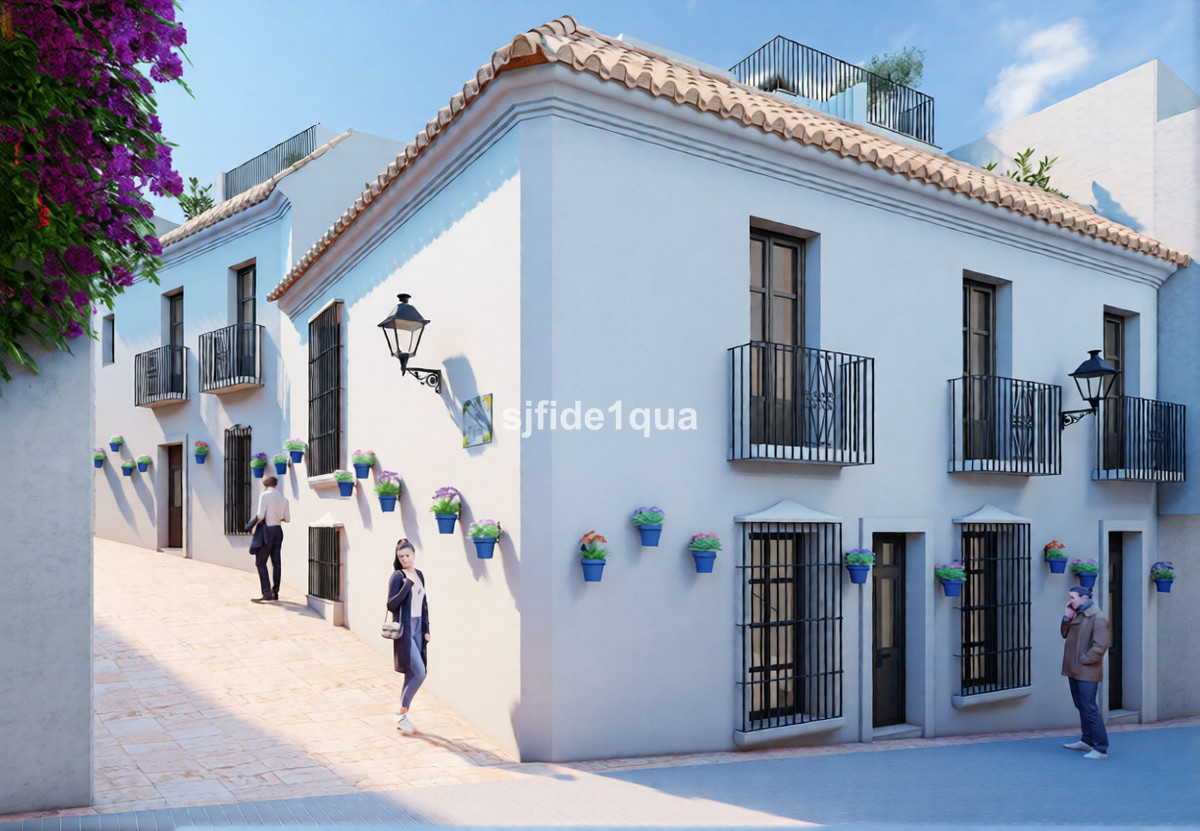 Maria Caridad – Estepona - whitewashed Andalusian facade with terracotta roof tiles, iron balconies and blue flower pots on a cobbled street