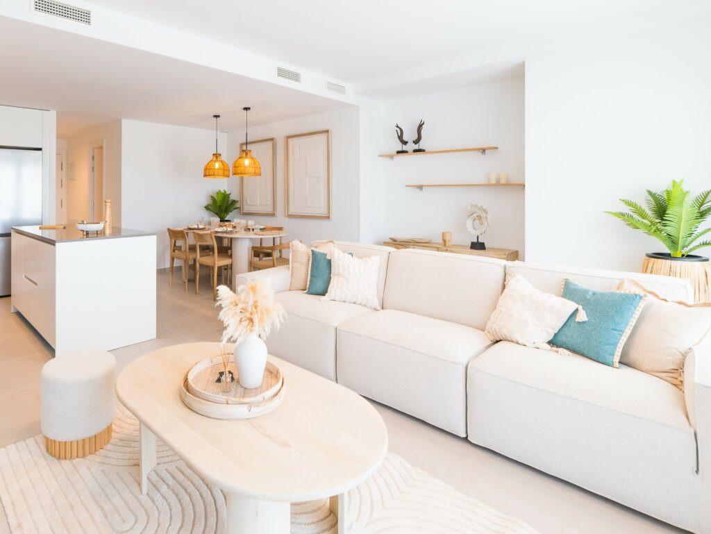 Oceana Gardens II – Cancelada - lichte open woon- en eetkamer met crèmekleurige bank, groenblauw kussens en sfeervolle hanglampen