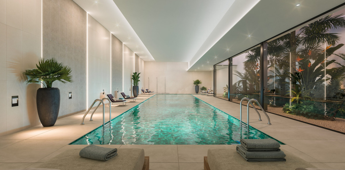 Origin – Marbella – luxuriöser Innenpool mit türkisfarbenem Wasser, Loungesesseln, Tropenpflanzen und raumhohen Glaswänden