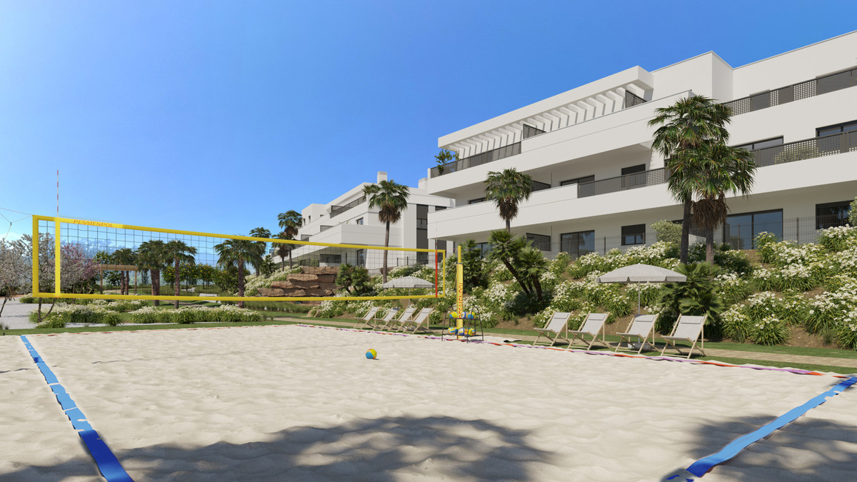 Serenity Gardens – Estepona - beachvolleybalveld met geel net naast aangelegde tuinen en modern wit appartementencomplex
