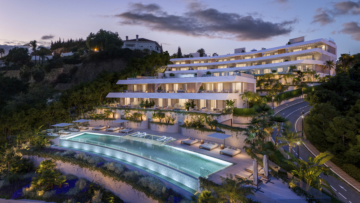 Solenne – Benahavís - luxury hillside residential complex with illuminated infinity pool, terraced gardens, and white modern facade at dusk