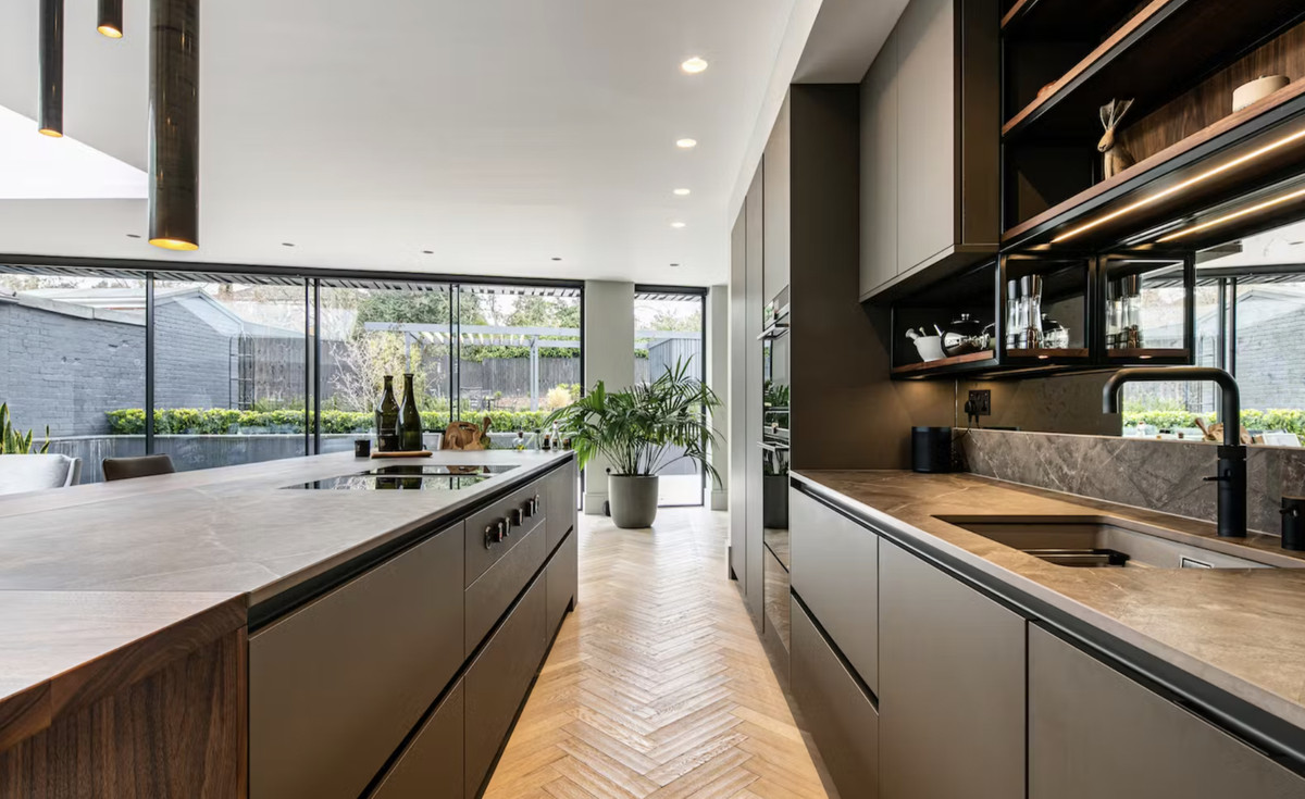 Villa 40 Monte Mayor – Benahavís – Elegante offene Küche mit Steinarbeitsplatten, dunklen Schränken, Fischgrätparkett und Gartenblick