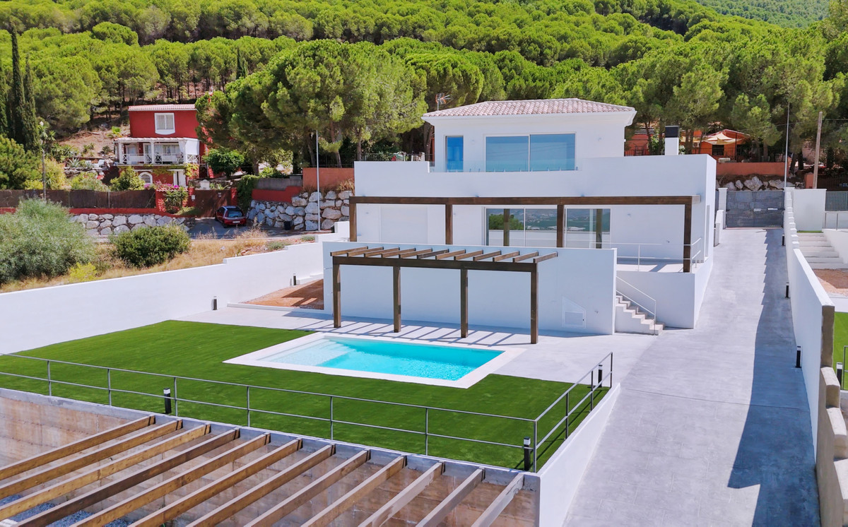 Villa Santhai 3 y 9 – Alhaurín de la Torre - luftfoto af hvid moderne villa med udendørs pool, pergola og grøn græsplæne mod skovklædt bakke