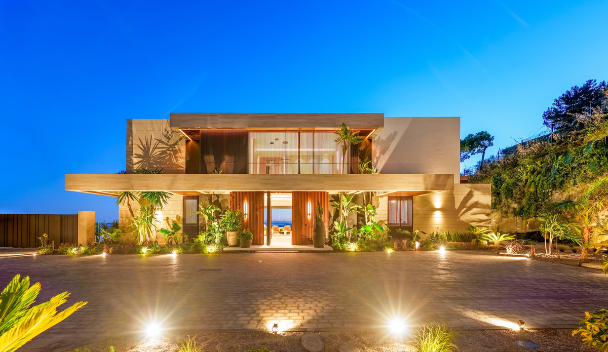 The Sky Marbella Villas – Benahavís – beleuchtete Fassade einer modernen Luxusvilla in der Abenddämmerung mit tropischem Grün und Meerblick