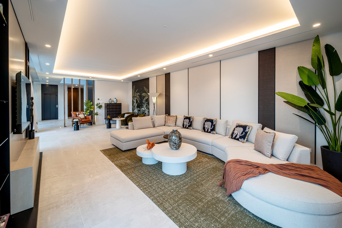 Villa Esmeralda – El Paraiso - ruime luxe woonkamer met gebogen witte hoekbank, indirecte verlichting en tropische plant