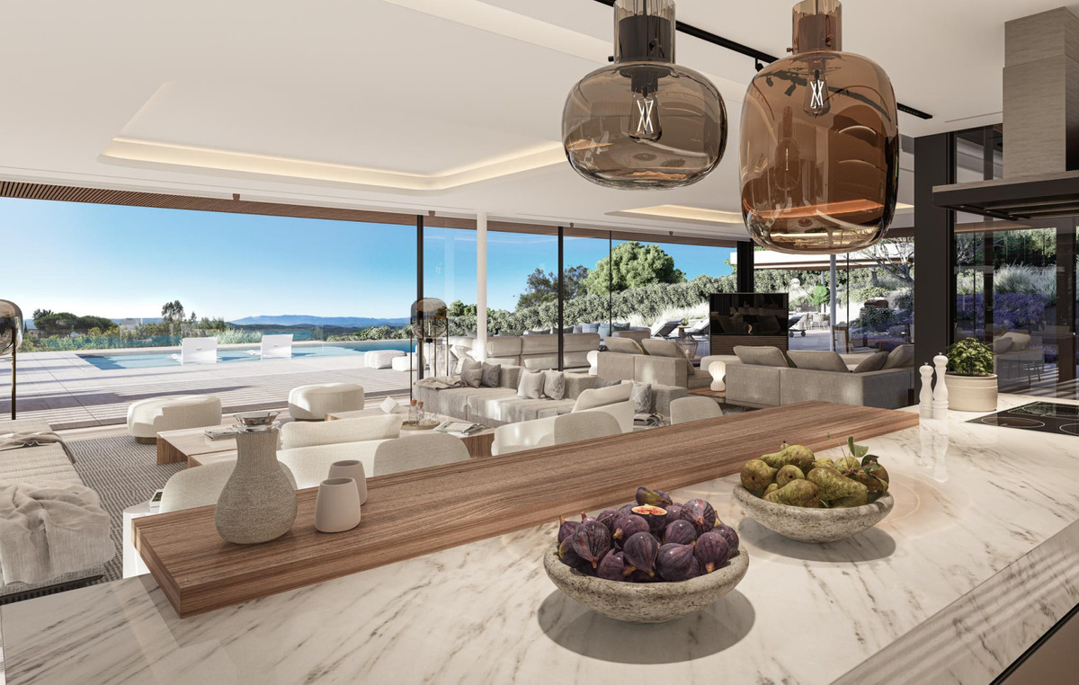 VILLA RETIRO – The Collection – Sotogrande - open-plan kitchen and living area with marble island, pendant lights, and pool views