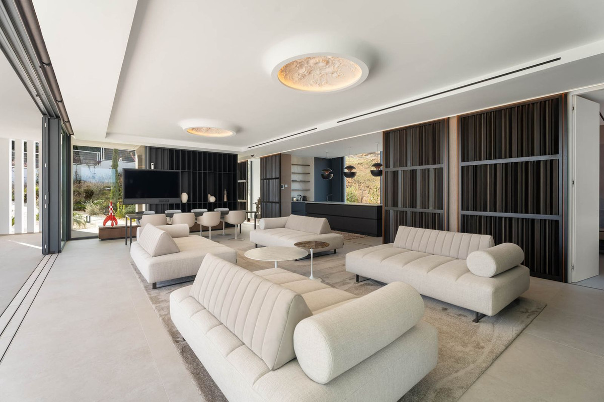 Tree Villas – La Cala Golf - ruime open woonkamer met crème hoekbanken, sfeervolle plafondverlichting en donkere houten wanden