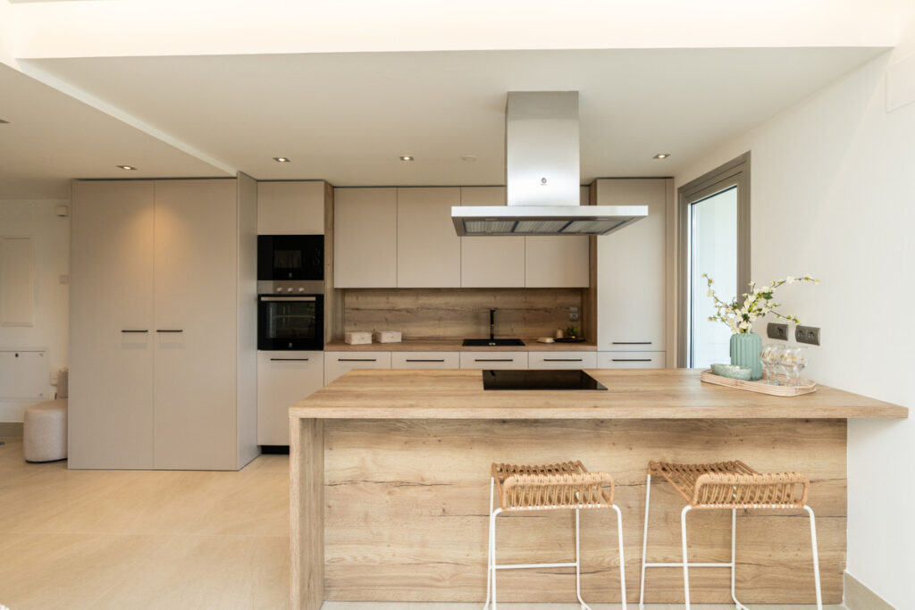 Solana Village – Fase 3 – La Cala Golf - modern open-plan kitchen with wood island, bar stools and integrated hood