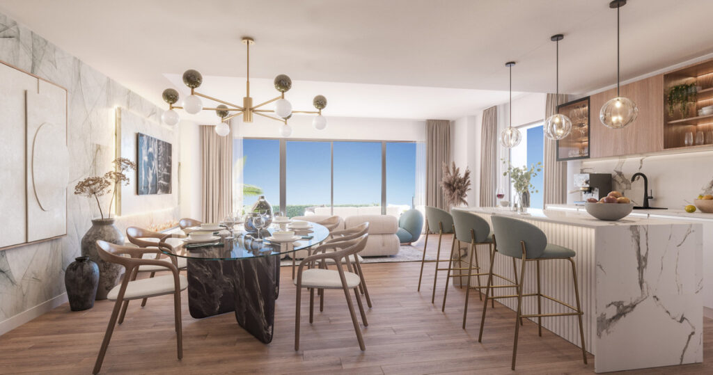 Soleia Living FASE II – El Chaparral - open-plan dining and kitchen area with marble island, sea views and gold pendant lighting