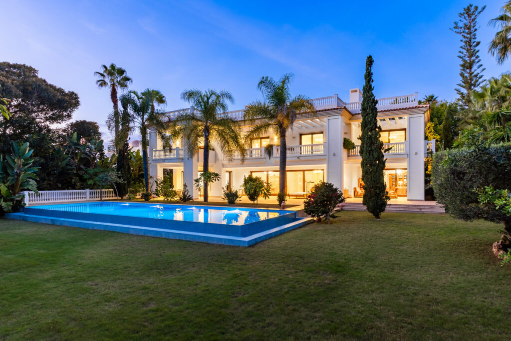 Villa Murcia – Estepona - luxury white villa exterior with illuminated pool and lush tropical gardens at dusk