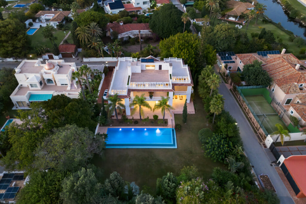 Villa Murcia – Estepona - aerial view of luxury villa with illuminated pool, lush gardens and palm trees at dusk