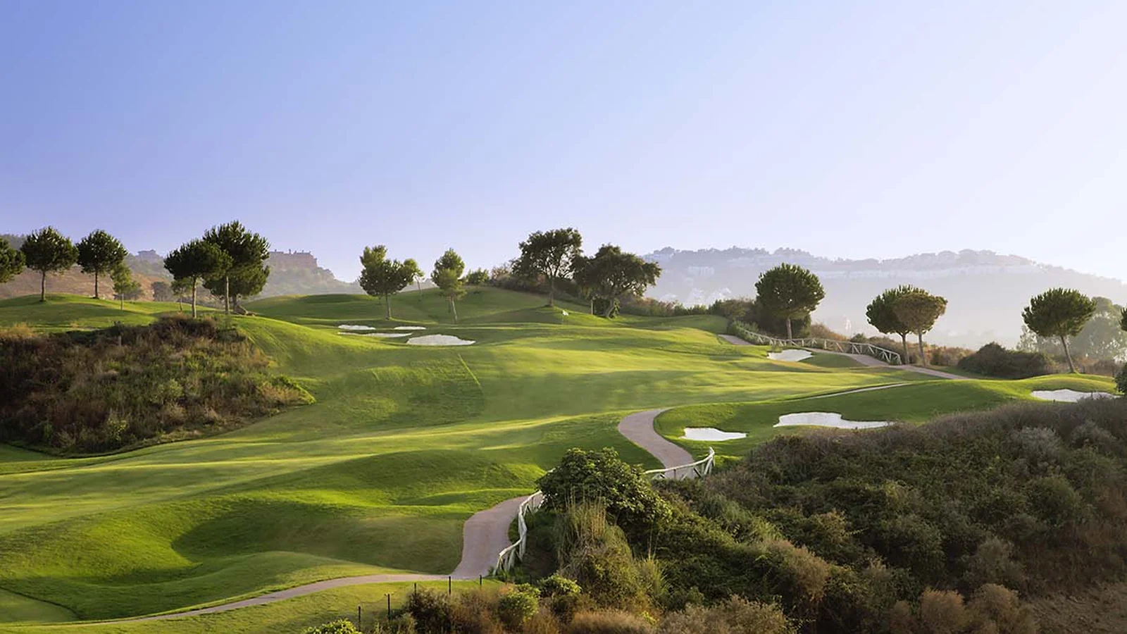 Hul seks på Campo América ved La Cala Golf Resort, med fairways og Sierra de Mijas bagved